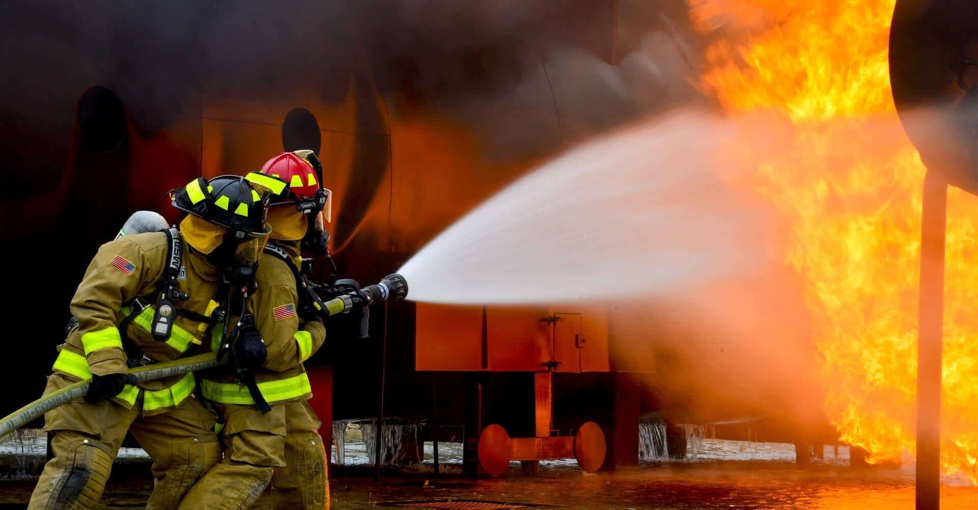 A fire fighter putting out a fire by using a hose